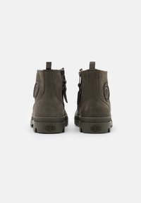 Grüne Wildleder-Stiefeletten mit strukturiertem Finish, versehen mit einem Reißverschluss auf der Rückseite, eingeprägtem Logo und robusten Gummisohlen.