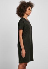 Rochie tricou din bumbac negru, cu mâneci scurte, croială lejeră, decolteu rotund și fante laterale. Textură netedă și lungime până la mijlocul coapselor.