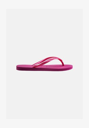 Sandale tong en caoutchouc rose avec semelle texturée et fines brides en forme de Y sur un fond gris clair uni.