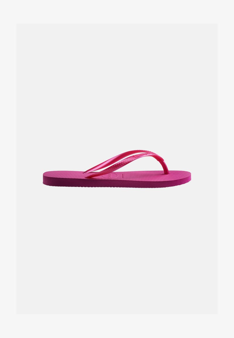 Ροζ λαστιχένιο σανδάλι με υφή στη σόλα και λεπτά λουράκια σε σχήμα Υ σε απλό γκρι φόντο.