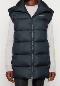 Tmavě modrá péřová vesta s vysokým límcem, zipovým uzávěrem a prošívaným designem. Na levé horní straně se nachází logo Columbia.