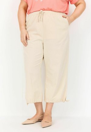Beige, korta joggers med elastisk midjeband och snörning. Har sidofickor och fransade fållar. Matchas med platta skor.