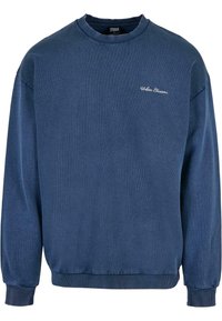 Felpa blu realizzata in un materiale morbido, con collo a giro, maniche lunghe, polsini a costine e un sottile logo bianco sul petto.