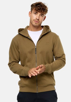 Olivengrøn zip-up hoodie med en tekstureret bomuldsblanding, ribbede manchetter og elastisk kant. Har en kængurulomme og et logo på brystet.
