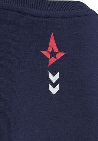 Marinblå sweatshirt med en röd stjärnlogotyp och tre vita chevronformer tryckta på baksidan, med en slät, texturerad tyg.