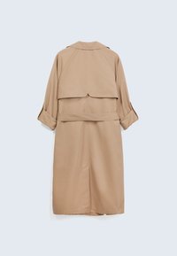 Beige trenchcoat med lös passform, bältat midja och ett lagerbakstycke. Har långa ärmar och en mjuk textur.