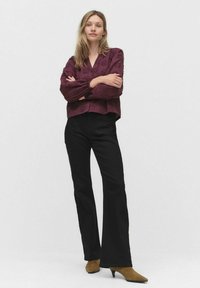 Bordeaux blouse met bloemtextuur en v-hals, gecombineerd met zwarte flared broek en bruine spitse hakken. Schoon, minimalistisch achtergrond.