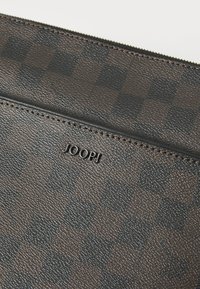 Brun mønstret lærveske med teksturert overflate, med glidelås-lukking og en liten preget logo som sier "JOOP!" nær den øverste sømmen.