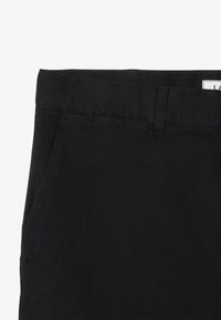 Pantalons noirs avec une texture en denim lisse, poches standard et une taille avec passants de ceinture. Le tissu est léger et se drape bien.