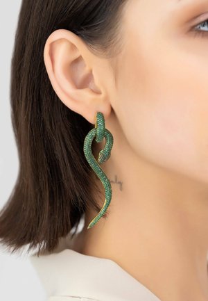 Green snake-shaped earrings, featuring intricate detailing and a textured surface, with shimmering accents and a gold-tone finish.
