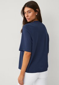 Navyblauw shirt met korte mouwen van een gladde stof, met een ontspannen pasvorm en een ronde halslijn, van achteren weergegeven met een lichte textuur.