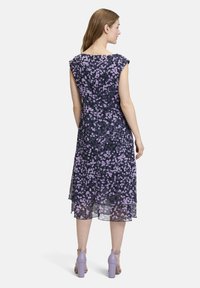 Ärmelloses Kleid aus transparentem, schichtweise gefertigtem Stoff mit einem dunkelblauen und lila floralen Muster; mit einem Bootsausschnitt und einem Reißverschluss im Rücken.
