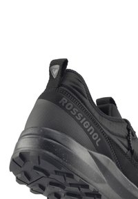 Černá sportovní bota s kompozitním svrškem a texturovanými detaily, robustní podrážkou a výrazným logem na boku.