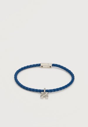 Μπλε πλεκτό δερμάτινο βραχιόλι με ασημένιο ορθογώνιο κούμπωμα και ένα μικρό ασημένιο τετράγωνο γούρι με γεωμετρικές περικοπές.