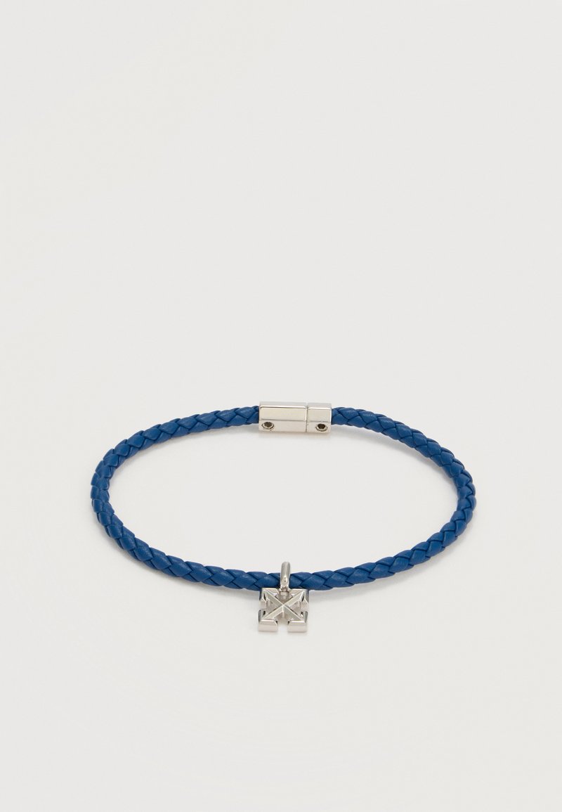 Μπλε πλεκτό δερμάτινο βραχιόλι με ασημένιο ορθογώνιο κούμπωμα και ένα μικρό ασημένιο τετράγωνο γούρι με γεωμετρικές περικοπές.