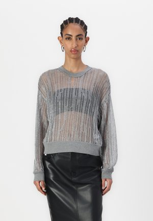 Maglione lavorato a maglia trasparente argento con vestibilità ampia, polsini e orlo grigio a coste, caratterizzato da una striscia orizzontale nera sul petto. Abbinato a una gonna nera.