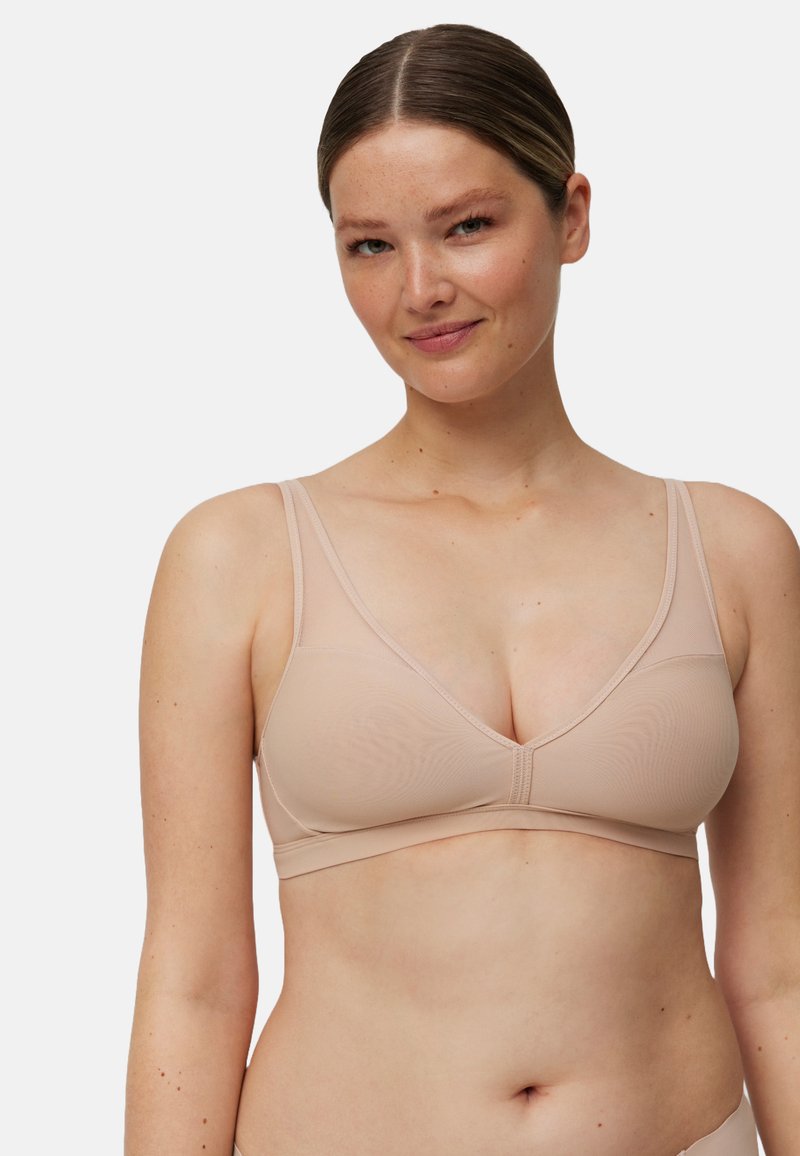 Bralette color nude con una tela suave, forma triangular, tirantes anchos y costuras mínimas. Presenta un sutil patrón texturizado en las copas.