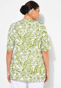 Top de manga corta en verde y blanco con un patrón de hojas, fabricado en un material ligero y con un corte relajado. La vista trasera muestra un escote redondo.