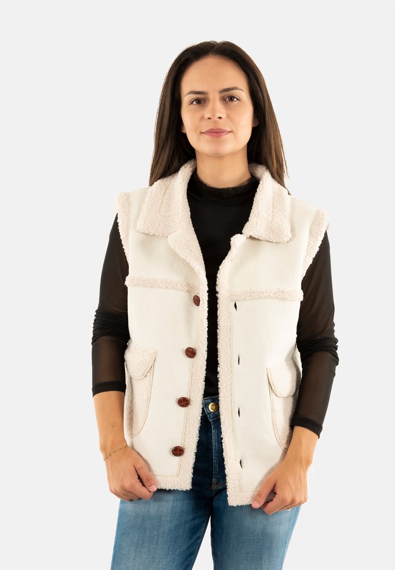 Chaleco de color claro con cuello y ribete suave y esponjoso, adornado con botones marrones, dos bolsillos frontales y un diseño sin mangas.