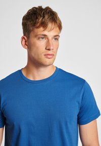 Niebieska bawełniana koszulka T-shirt, z okrągłym dekoltem, krótkie rękawy, gładka faktura, minimalistyczny design, bez widocznych wzorów ani akcentów, dopasowany krój.