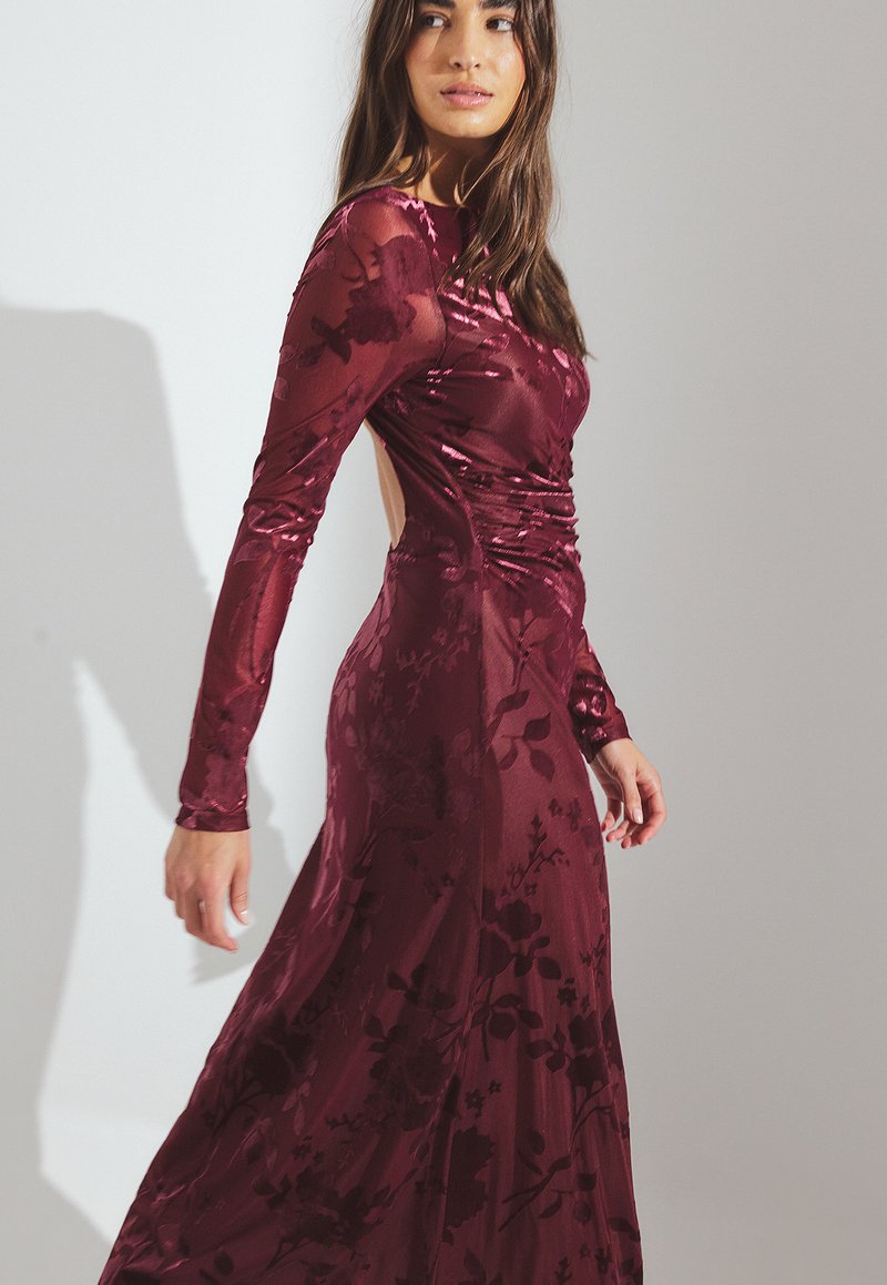 Mörkröd klänning med långa ärmar och blommönster, figurnära liv, sidskärning och svävande kjol, tillverkad av glatt, lätt tyg.