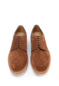 Scarpe in suede marrone con una superficie liscia, punta rotonda e cinque occhielli per i lacci. Caratterizzate da una cucitura a contrasto, suola in gomma e design minimal.