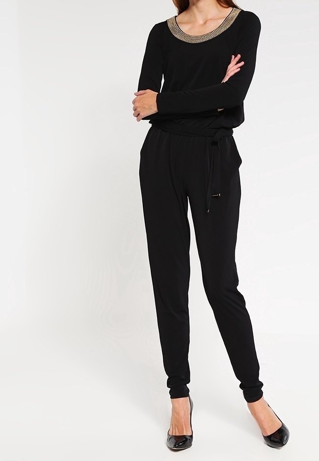 Combinaison noire avec un col arrondi orné d'accents métalliques, manches longues, taille cintrée, et pantalon à coupe effilée.