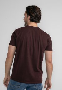Burgundské tričko s krátkým rukávem a kulatým výstřihem, vyrobené z měkké bavlněné látky, jednoduchý design a rovný střih. Má hladkou texturu.