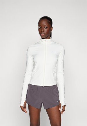 White zip-up athletic jacket with long sleeves and a high collar, paired with dark grey shorts featuring a small logo. Smooth, fitted material.