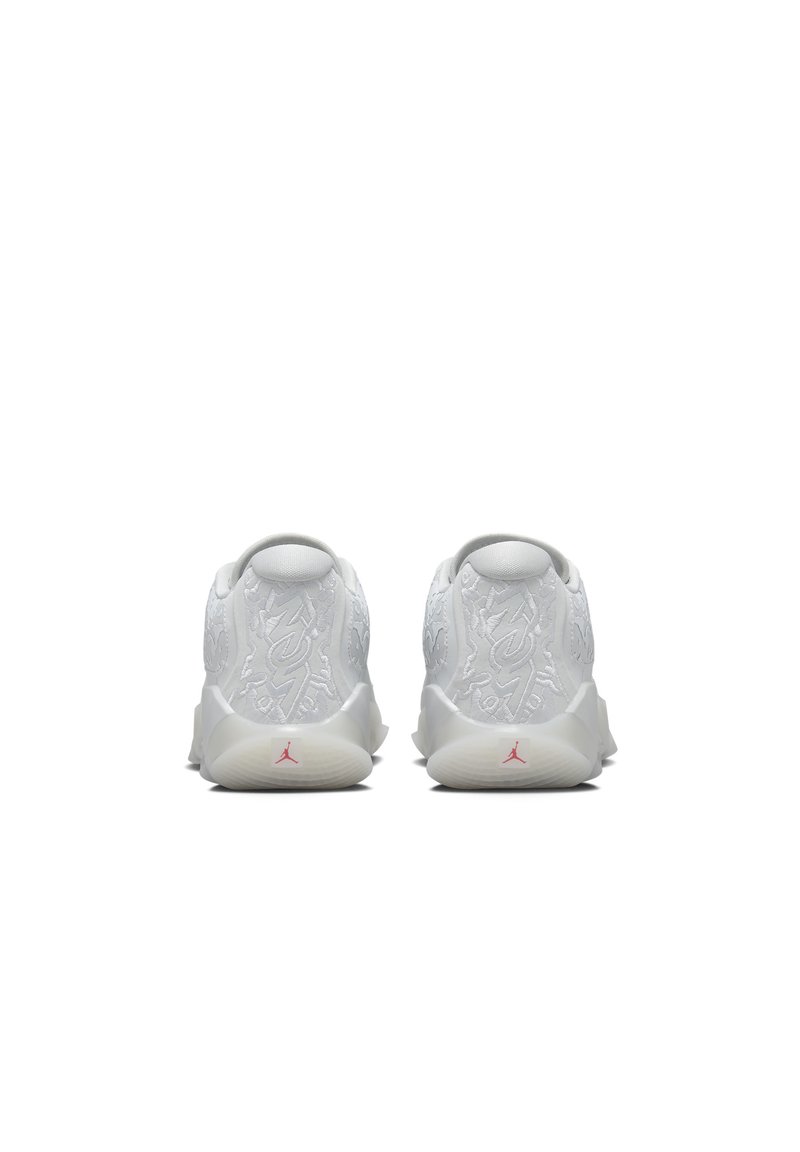 Baskets blanches avec des détails en relief sur le dessus, un talon rembourré et un logo rouge à l'arrière. Matériau lisse et forme arrondie.