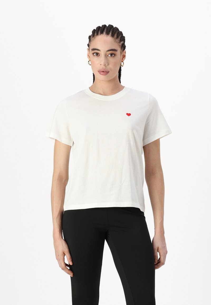 Witte katoenen T-shirt met korte mouwen, voorzien van een klein rood hartlogo op de linkerkant van de borst. Rechte snit, zachte textuur en een minimalistisch ontwerp.