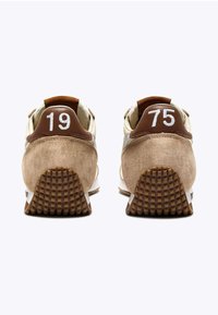 Sneaker in suede marrone con accenti beige, caratterizzati da numeri ricamati bianchi "19" e "75" sul tallone, suola in gomma testurizzata.