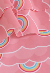 Rosa tyg med ett vågmönster och regnbågar i flera färger. Mjuk textur med släta kanter och en lätt design.