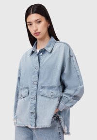 Giacca in denim blu chiaro con colletto, due tasche anteriori e orlo strappato. Caratterizzata da una vestibilità ampia e chiusura a bottoni.
