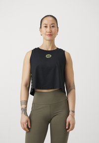 Svart kort topp med rund halsringning, med en liten gul logotyp. Matchas med högmidjade olivgröna leggings.