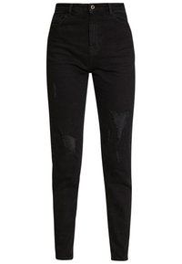 Pantalones vaqueros de mezclilla negra con corte ajustado, que presentan detalles desgastados y parches deshilachados, diseño de cinco bolsillos, y cremallera con cierre de botón.