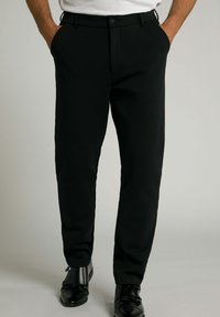 Schwarze Hose mit schmaler Passform, gefertigt aus einem glatten Stoff. Verfügt über einen Knopfverschluss, Seitentaschen und eine leichte Verengung am Knöchel.