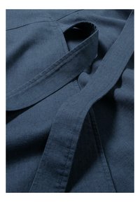 Nahaufnahme eines blauen Stoffes mit glatter Textur, sichtbaren Nähten und einem fließenden Design. Enthält Bändchen zum Verschließen.