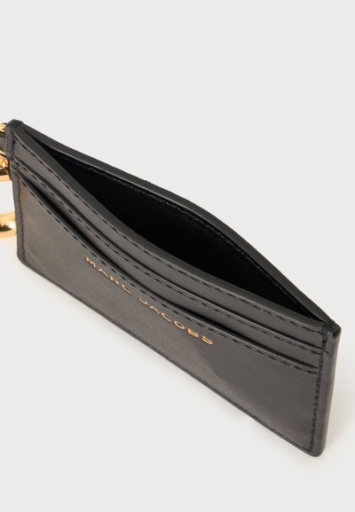 Porte-cartes en cuir noir avec logo Marc Jacobs doré, trois emplacements pour cartes, ouverture par le haut, et anneau de porte-clés doré attaché.