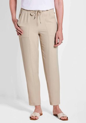 Beige Pull-On-Hosen mit einem Kordelzugbund, seitlichen Taschen, flachen vorderen Nähten und einem schmal zulaufenden Bein Design. Getragen mit hellen Schlupfsandalen.