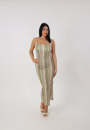 Abito lungo beige con motivo a zigzag verde e marrone. Presenta spalline sottili, scollatura quadrata e una spaccatura laterale per facilitare i movimenti.