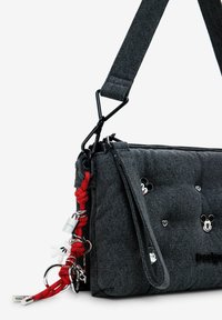 Graue Jeans-Umhängetasche mit roten Akzenten, besticht durch eine gesteppte Textur, kleine Mickey-Mouse-Motive und verschiedene metallische Details.