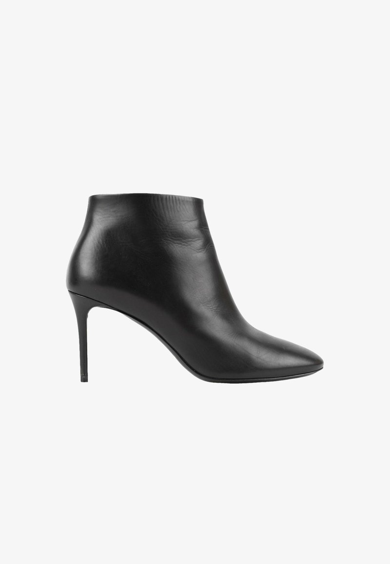 Bottine en cuir noir avec bout pointu et talon haut fin sur fond blanc.