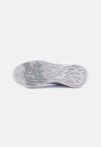 Semelle de sneaker blanche avec motifs de grip texturés. Le design présente un accent gris et des lignes ondulées, offrant une esthétique sportive et une traction.