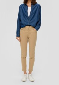 Denimskjorta med knappar och långa ärmar, khakifärgade slim-fit byxor och vita sneakers. Anmärkningsvärd sömnad och en avslappnad passform i en neutral färgpalett.