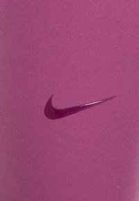 Tessuto sportivo rosa con una superficie liscia presenta un logo Nike di un rosa scuro in una finitura lucida sobria, posizionato nell'angolo in basso a destra.