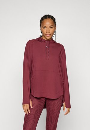 Maroon long-sleeve hoodie with a drawstring hood, kangaroo pocket, and side slits, paired with patterned maroon leggings. Smooth, lightweight fabric.
