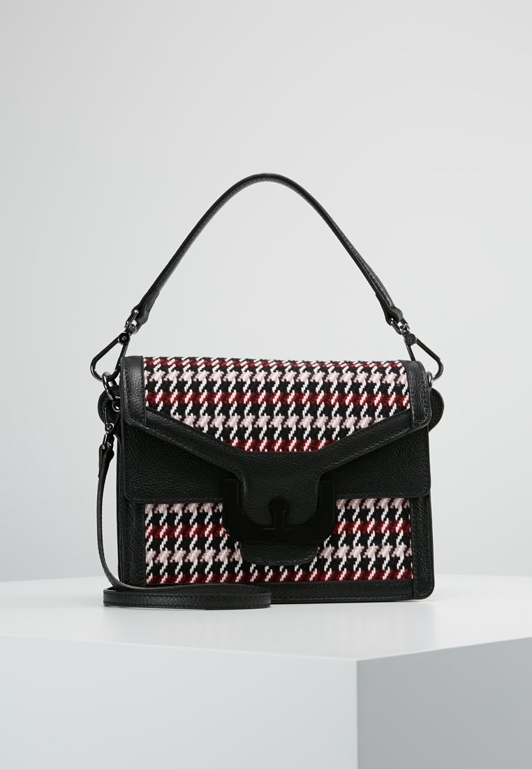 Sac à main en cuir noir avec tissu pied-de-poule rouge, blanc et noir, poignée supérieure, rabat avant et bandoulière amovible sur une surface blanche.
