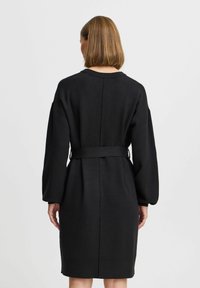 Must mustdress musta volüümikate varrukatega ja vöökohaga. Sile tekstuur ja sirge lõige, selja peal keskse õmblusega.