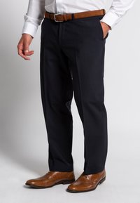 Marineblaues Anzughose aus glattem Stoff, mit geradem Bein, seitlichen Taschen, kombiniert mit hellbraunen Lederschuhen mit Brogue-Details.